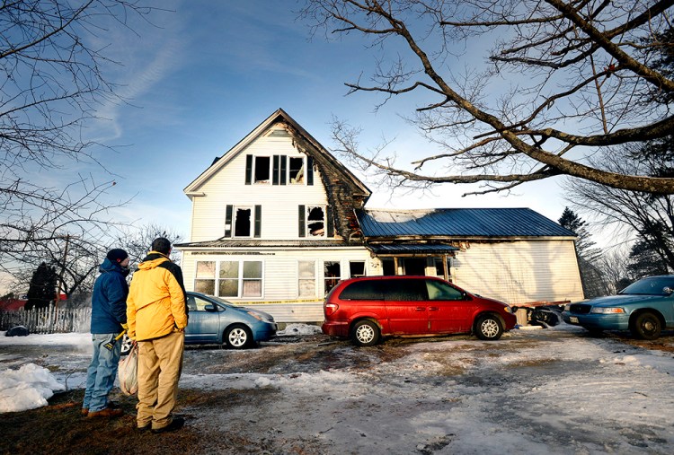David Buck looks over his fire-damaged home at 1573 Goodwins Mills Road in Waterboro along with his son Brian Buck, left, on Monday. Shawn Patrick Ouellette / Staff Photographer 