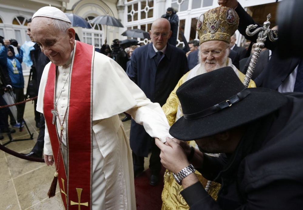 A pilgrim kisses the hand of Pope Francis as Ecumenical Patriarch Bartholomew I follows him after a holy liturgy at the Patriarchal Church of St. George in Istanbul on Sunday. Pope Francis ended his three-day visit to Turkey on Sunday.