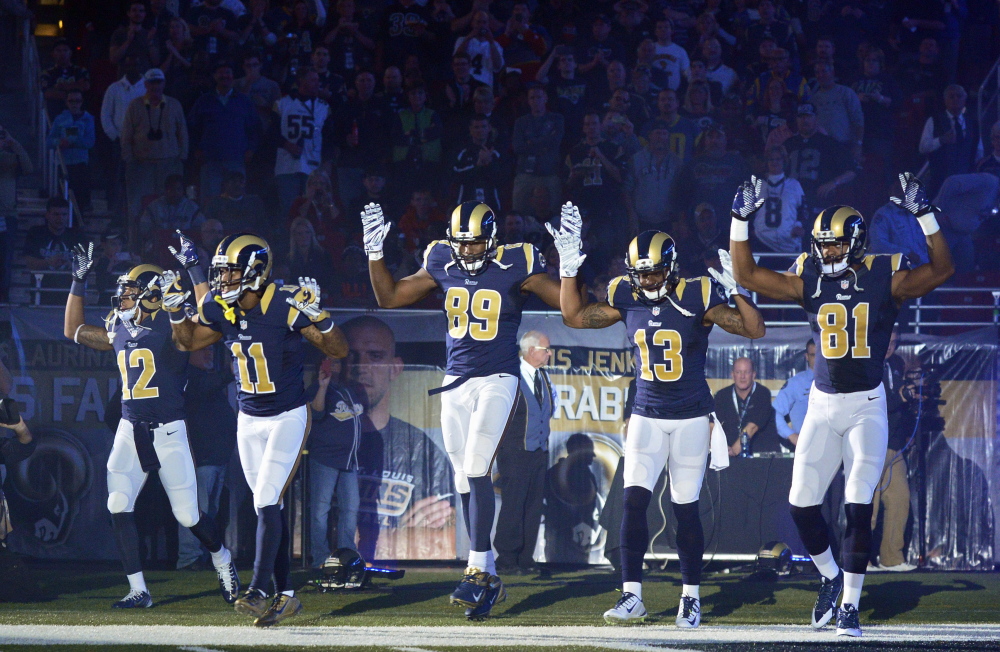 St. Louis players, from left, Stedman Bailey, Tavon Austin, Jared Cook, Chris Givens and Kenny Britt take the field with a “Hands Up., Don’t Shoot!” gesture before Sunday’s game against Oakland in St. Louis. The players say they were showing their support for the community.