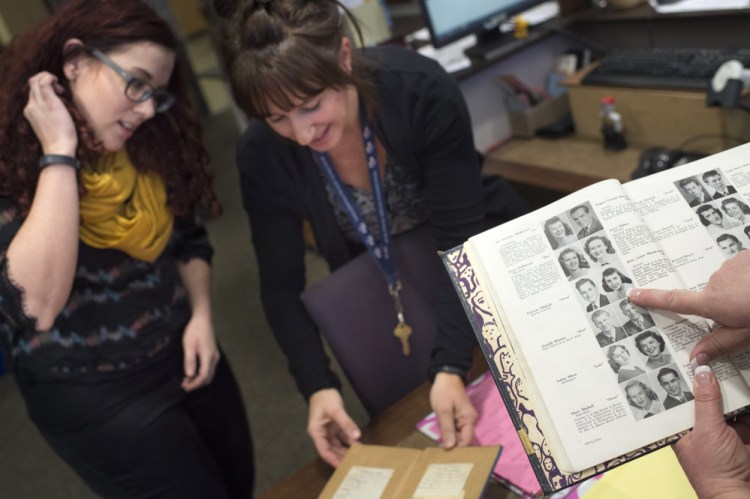Rogers High School librarian Becky Huss, left, checks out a long-overdue copy of “Gone With The Wind,” with school literacy coach Tracy Schumacher, center, as school Principal Lori Wyborney finds a photo of the last student to check out the book in a 1949 yearbook in Spokane, Wash.