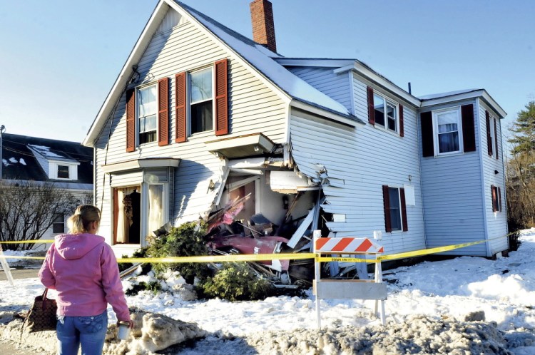 Shannon Thaller, a housekeeper for the owners of this home, surveys the damage left after a tractor-trailer struck the building on Madison Avenue in Skowhegan Tuesday. Thaller said she couldn’t believe the damage and was glad no one was home when the incident occurred.