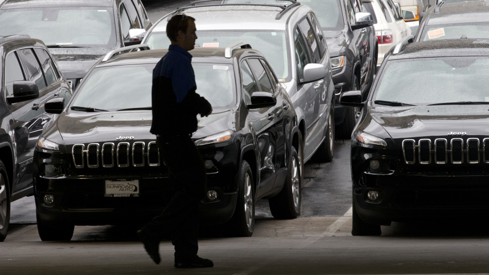 A worker on a Chrysler car lot passes rows of parked vehicles – most of them Jeep SUVs – on Tuesday in San Diego. Chrysler has posted its best November in 13 years.