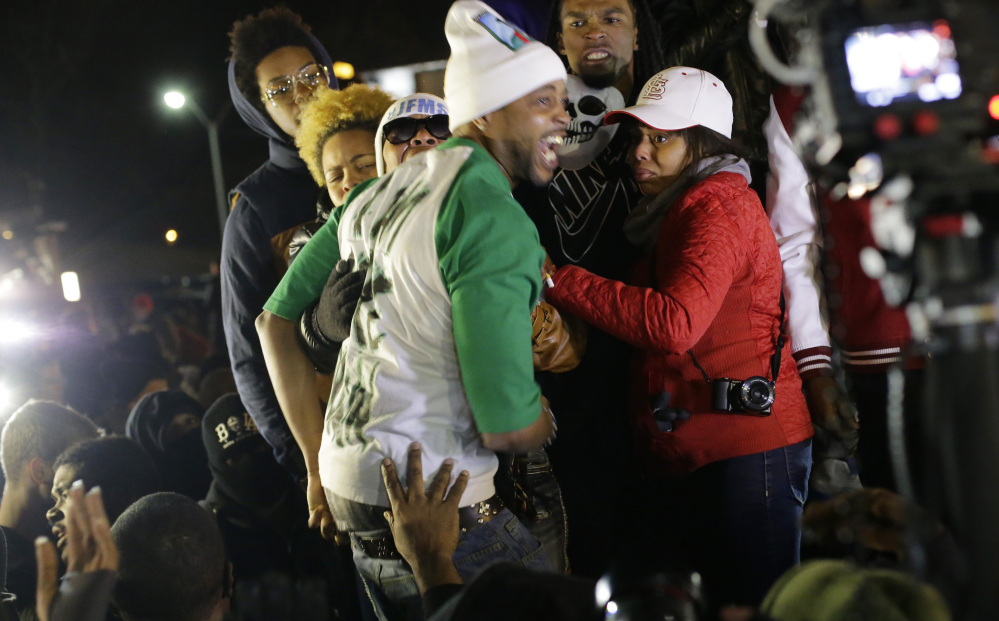 Michael Brown’s stepfather, Louis Head, center front, and Brown’s mother, Lesley McSpadden, wearing sunglasses, hear the grand jury’s decision Nov. 24 in Ferguson, Mo.