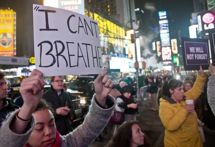 Protesters carry signs in Times Square on Wednesday evening in reaction to a grand jury’s decision not to indict a police officer in the death of Eric Garner in New York.