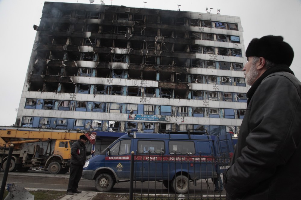 A police minivan is parked outside the burned publishing house in Grozny, Chechnya, on Thursday, where a gun battle broke out just hours before Russian President Vladimir Putin gave his annual state of the nation address in Moscow.