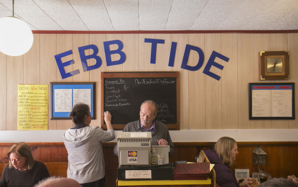 Peter Gilchrist, above, adjusts the cash register Thursday at the Ebb Tide restaurant in Boothbay Harbor while waitress Rose Marie Hodgdon wipes one of the specials off the menu board. Gilchrist and his wife, Nancy, closed the restaurant Thursday, exactly 40 years after they signed the papers to buy it.