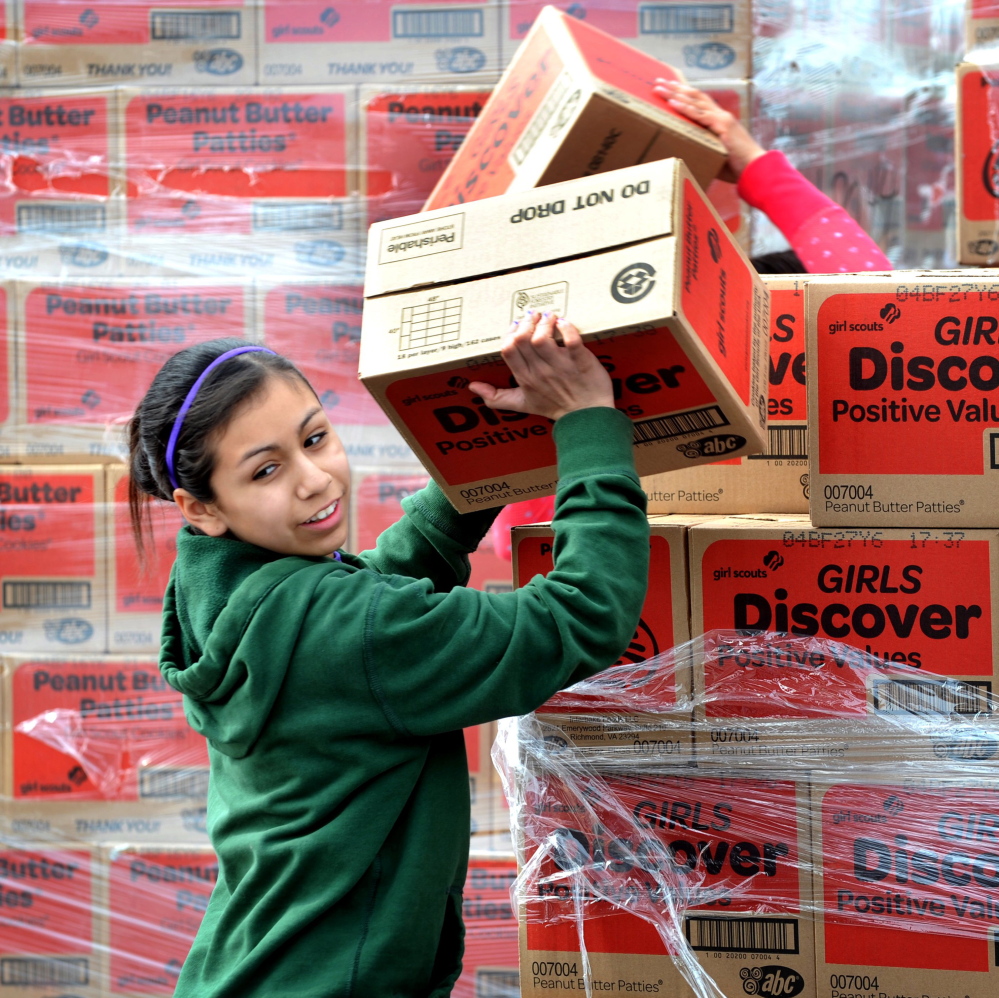 Paola Garcia stacks Girl Scout cookie boxes in Modesto, Calif. The scouts now allow online sales, but there are concerns about security issues and Internet use.