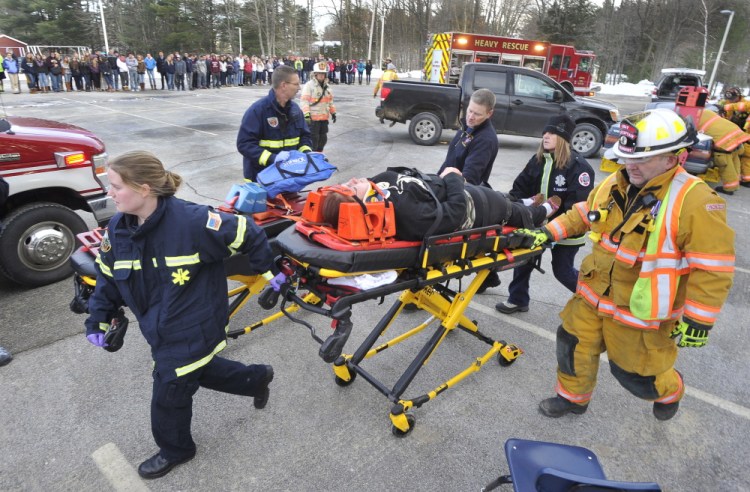 During a mock crash demonstration at Gray-New Gloucester High School on Friday, Gray Fire and Rescue personnel transport senior Tamica McNally as part of an effort to show students what can happen when texting while driving.