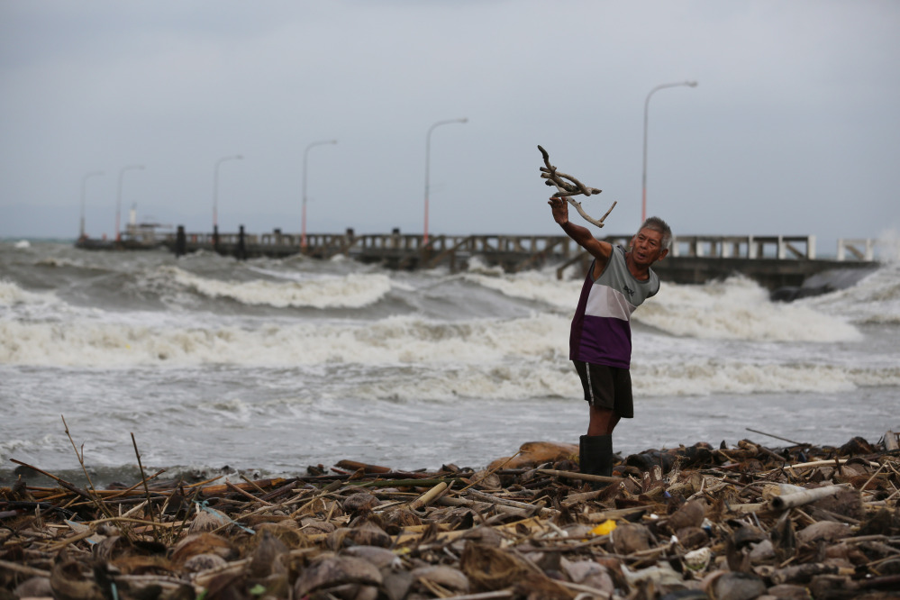 A man throws wood along the shore as strong waves from Typhoon Hagupit hit Atimonan, Quezon province, eastern Philippines, Saturday. Haunted by Typhoon Haiyan’s massive devastation last year, more than 600,000 people fled Philippine villages and the military went on full alert Saturday to brace for a powerful storm only hours away from the country’s eastern coast.