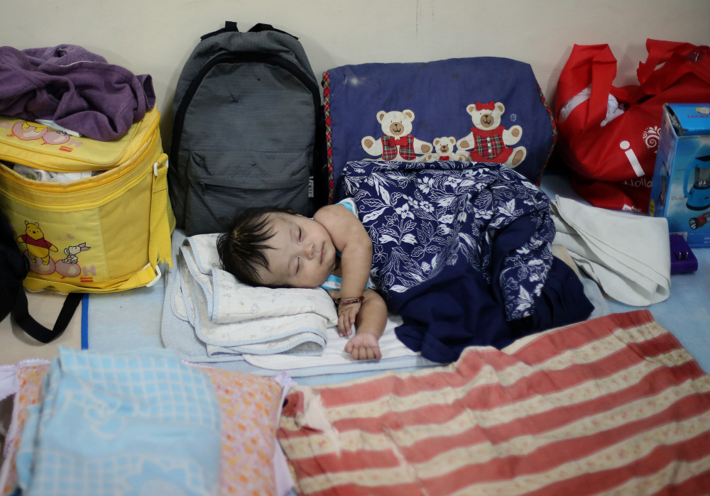 Filipino Jonrey Pawang sleeps beside his family’s belongings as they take refuge at a school used as an evacuation center,  in Legazpi in the eastern Philippines on Saturday.