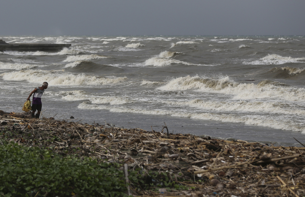 A man walks along the shore as strong waves from Typhoon Hagupit hit Atimonan in the eastern Philippines on Saturday. Forecasters say Typhoon Hagupit’s sustained winds and gusts are strong enough to set off deadly storm surges and landslides and cause heavy damage.