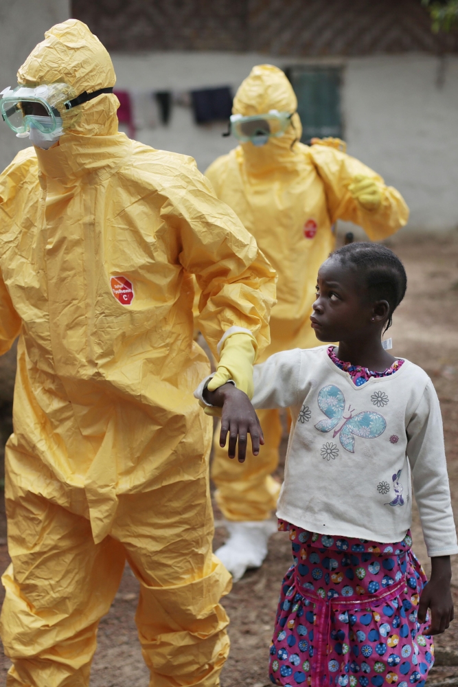 Health care workers escort a 9-year-old who showed symptoms of Ebola. Two doctors in Sierra Leone died from the virus Friday. Health care workers are among the most at risk of contracting the disease..