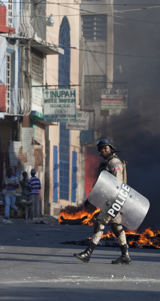 A police officer is framed by burning debris in Port-au-Prince, Haiti, on Saturday.