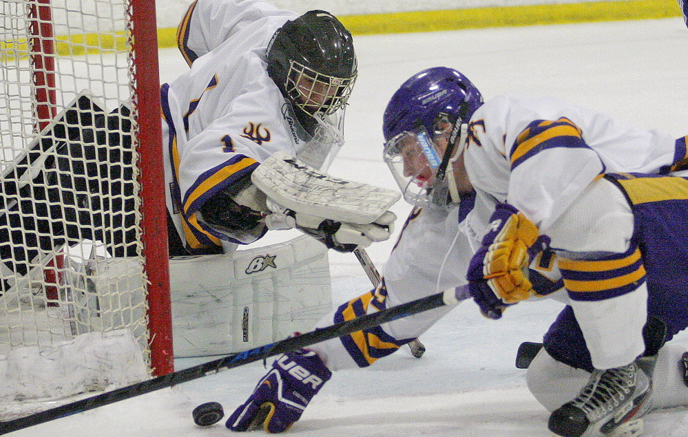 Cheverus goalie Kyle Severance and teammate James Kane try to keep the puck out of the net Saturday in a hockey season opener against Lewiston at Portland Ice Arena. Severance made 36 saves in a 3-2 overtime victory.