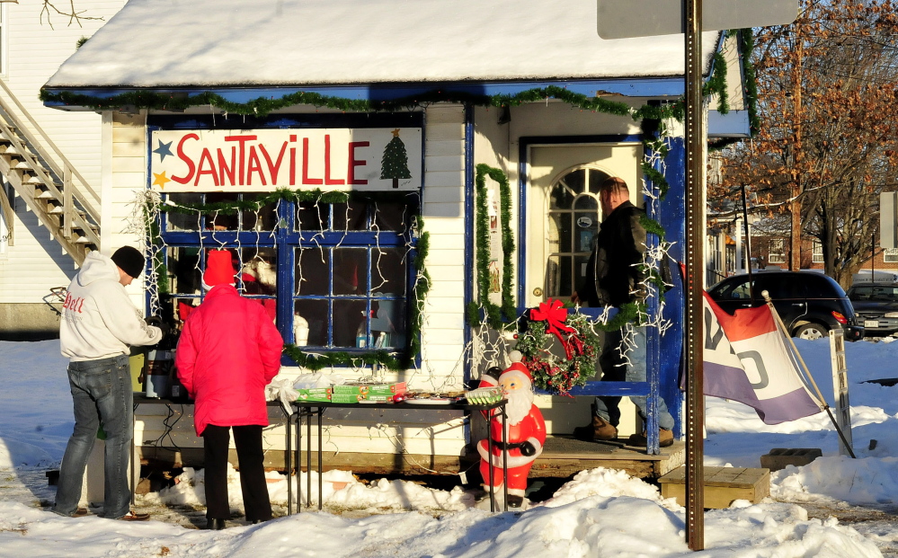 Santa’s helpers C.J. Duplessie, left, and Tina Worthley set out treats and hot coffee outside Santaville on Main Street in Madison.