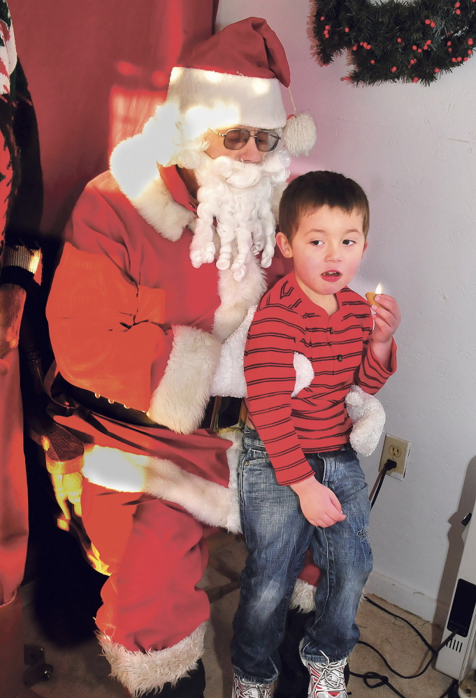 Between cookie bites, 3-year-old Sebastion Christie tells Stephen Foshay, dressed as Santa, what he wants for Christmas .