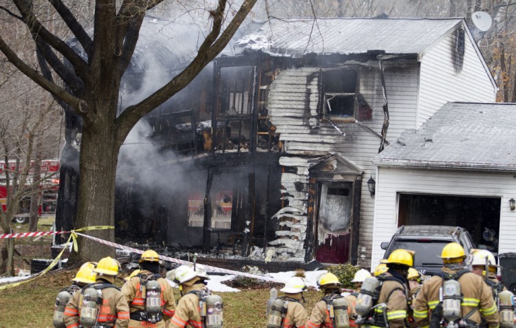 Montgomery County, Md., firefighters stand outside a house where a small private jet crashed in Gaithersburg, Md., Monday.