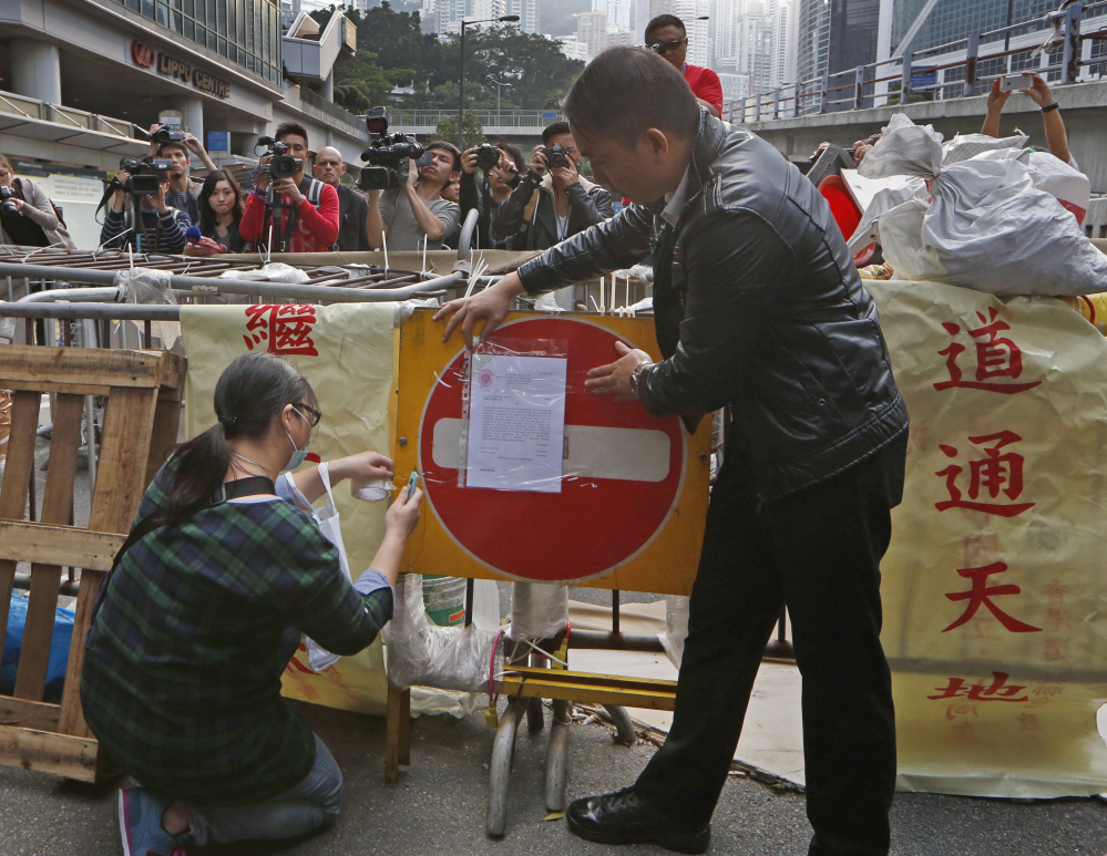 Hong Kong authorities post an injunction document on a barricade set up by pro-democracy protesters at the occupied area outside government headquarters Tuesday.