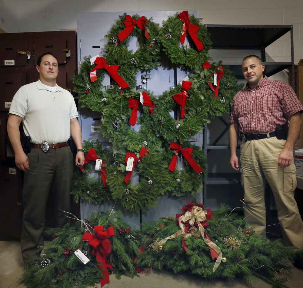 SACO, ME - DECEMBER 12:  Saco police detectives Jeffrey Cook, left, and Daryen Granata pose with the nine wreaths and two large holiday bouquets that were stolen from graves at Laurel Hill Cemetery. Today an Old Orchard Beach woman turned herself in after a warrant was put out for her arrest. Jeffrey Holland, deputy chief of police, joked that the department has a pleasant holiday smell to it now. (Photo by Derek Davis/Staff Photographer)