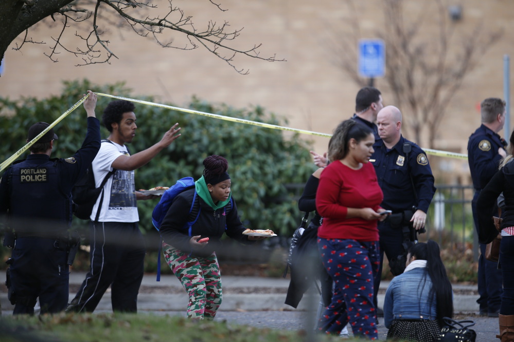 Officials direct youth at the scene of a shooting at Rosemary Anderson High School in Portland, Oregon, on Friday.