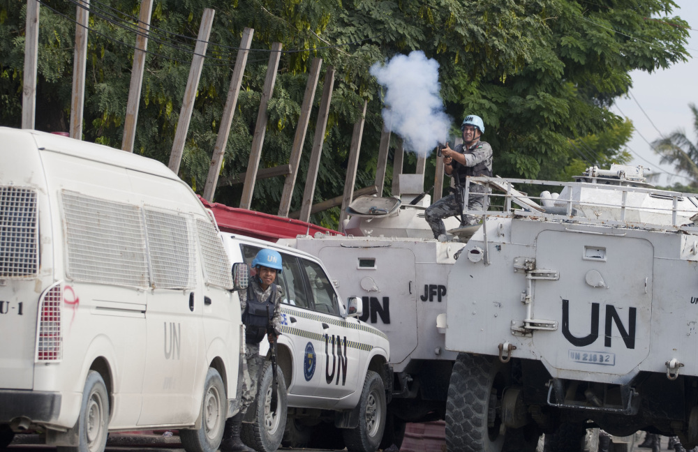 A Jordanian soldier from the U.N. peacekeeping force in Port-au-Prince, Haiti, fires tear gas at protesters demanding new government leadership on Friday. The protest occurred hours before President Michel Martelly discussed a report calling for a new consensus government.