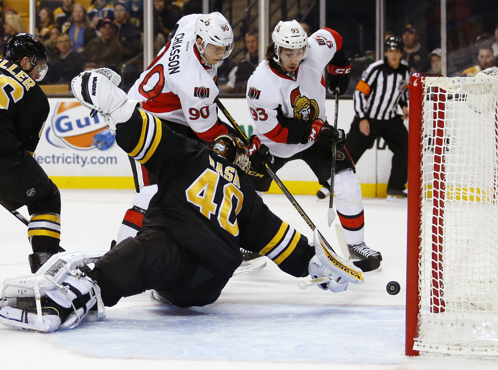 Ottawa’s Alex Chiasson, center, and Mika Zibanejad, right, chase a puck in the crease behind Bruins goalie Tuukka Rask during the first period of Saturday’s game in Boston. The Senators won 3-2 on Bobby Ryan’s shootout goal.
