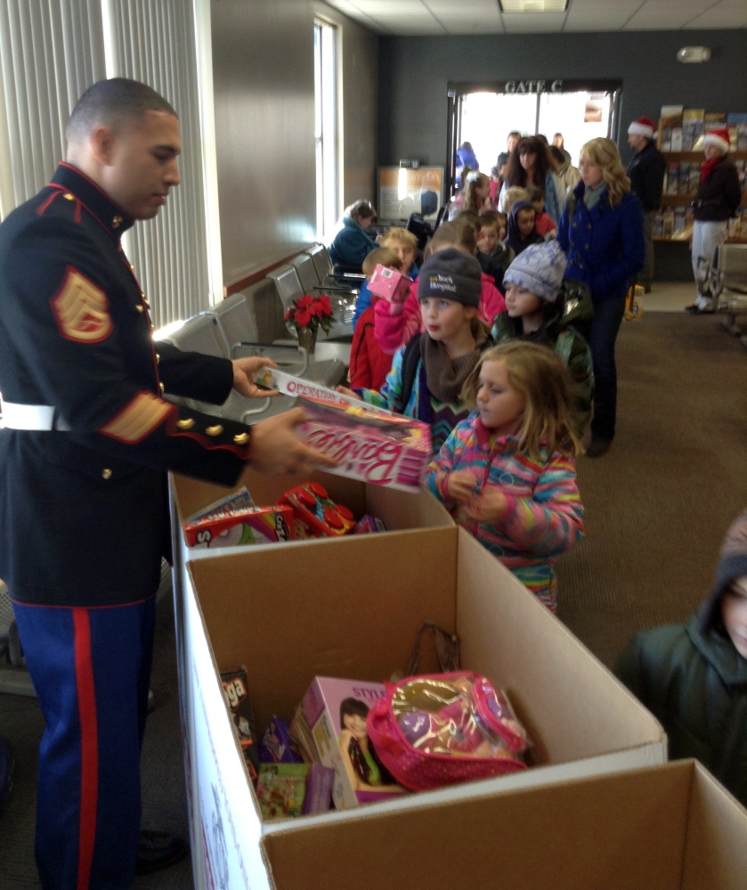Wells Elementary School students deliver Christmas presents in Portland recently as part of their annual giving campaign to benefit Toys for Tots. The project was administered by U.S. Marine Corps members, who received the donations and spoke to the children about how the program works. The students, their teachers and a few parents traveled to Portland on the Amtrak Downeaster, a journey the school has made annually since 2010. Photo by Reg Bennett.