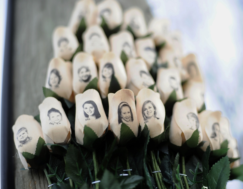 In this Jan. 14, 2013 file photo, white roses with the faces of victims of the Sandy Hook Elementary School shooting are attached to a telephone pole near the school on the one-month anniversary of the shooting that left 26 dead in Newtown, Conn.