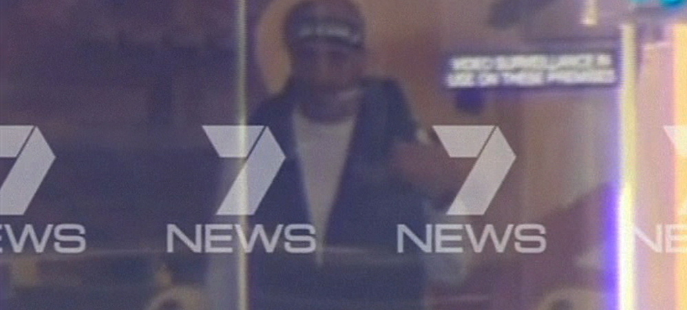 These images taken from video show, above, a man believed to be a gunman inside a Sydney cafe and, top, people inside the cafe holding what appears to be a black flag with white Arabic writing on it.