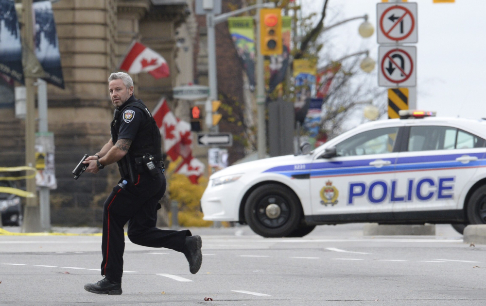 An Ottawa police officer runs with his weapon drawn outside Parliament Hill on Oct. 22. Radical Muslim Michael Zehaf-Bibeau’s killing of a soldier at a war memorial outside Canada’s parliament is one of many attacks by solo terrorists.