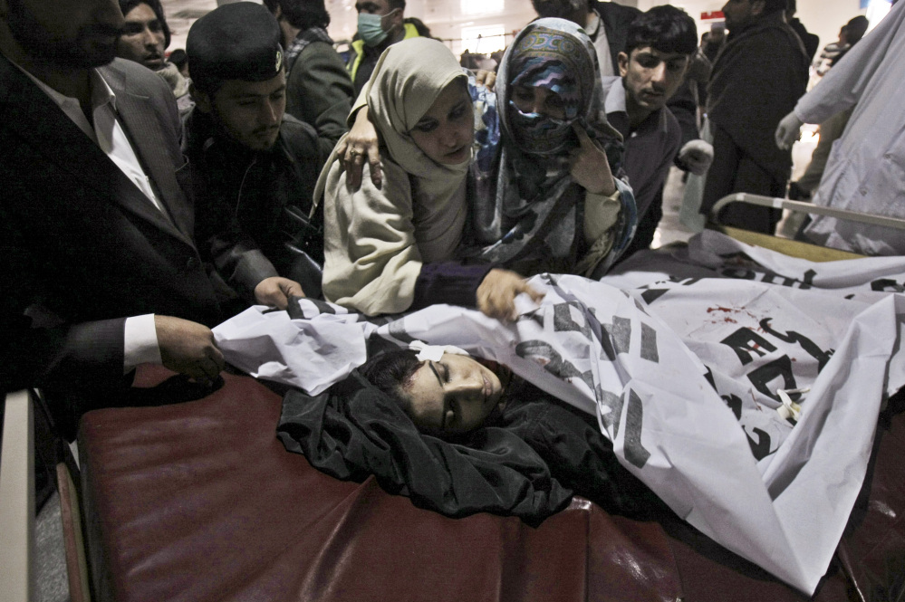 Relatives of a victim of a Taliban attack in a school, mourn over her lifeless body at a hospital in Peshawar, Pakistan, Tuesday.
