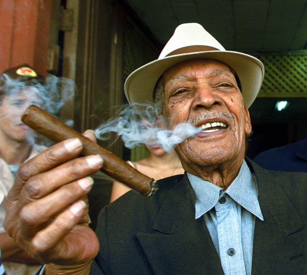 Cuban singer Francisco Repilado "Compay Segundo", 94, smokes a cigar he rolled himself Thursday Feb. 22, 2001, in Havana, Cuba. Cigar aficionados from as far away as Israel and Hong Kong visited tobacco farms and factories and savored new cigar brands this week during an annual celebration of this nation's world-famous stogies. (AP Photo/Jose Goitia)