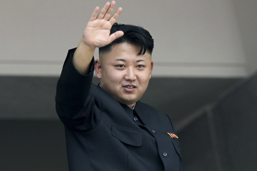 North Korea’s leader Kim Jong Un waves to spectators at a military parade.