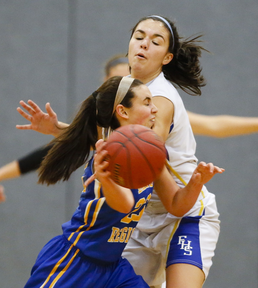 Falmouth’s Dayna Vasconcelos reaches for the ball as Lake Region’s Spencer True attempts to advance it during a girls’ basketball game in Falmouth on Thursday. The Yachtsmen won 42-41.
