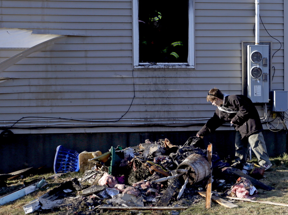 Greg Ballou, 26, of Freeport, looks through the rubble of a fire that destroyed his home on Varney Road on Saturday. Ballou and his wife, Ardelle, lost a cat and a dog in the blaze.