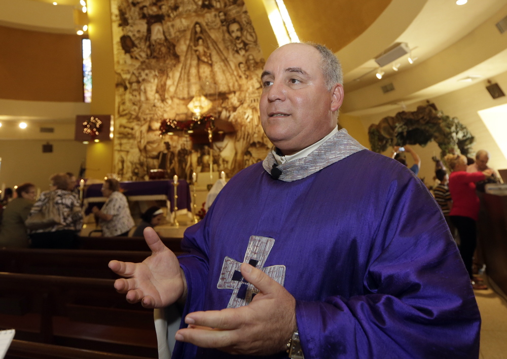 The Rev. Juan Rumin Dominguez talks to a reporter at Our Lady of Charity Catholic Church in Miami. 