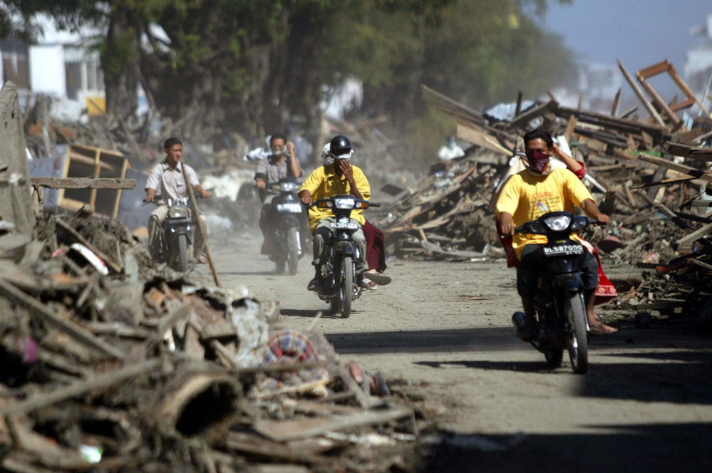 Motorists ride through debris in Banda Aceh, Indonesia, in December 2004 after a gigantic wave hit. The city is now almost totally restored.