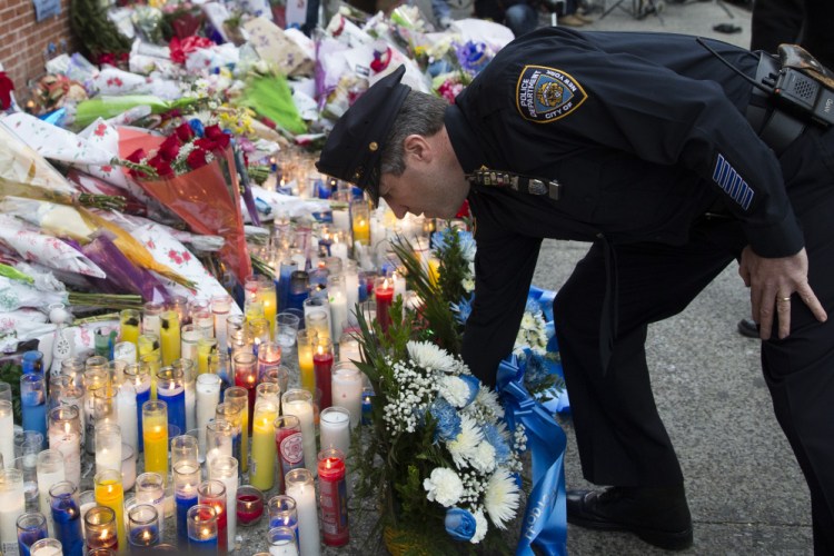 Patrick Lynch, president of the Patrolman’s Benevolent Association, places flowers at a makeshift memorial on Monday near the site in Brooklyn where New York police officers Rafael Ramos and Wenjian Liu were killed Saturday. Police say Ismaaiyl Brinsley ambushed the officers in their patrol car in broad daylight before killing himself in a subway station.