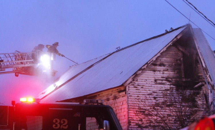A Biddeford firefighter vents the roof of a home at 25 River Road in Biddeford on Tuesday.