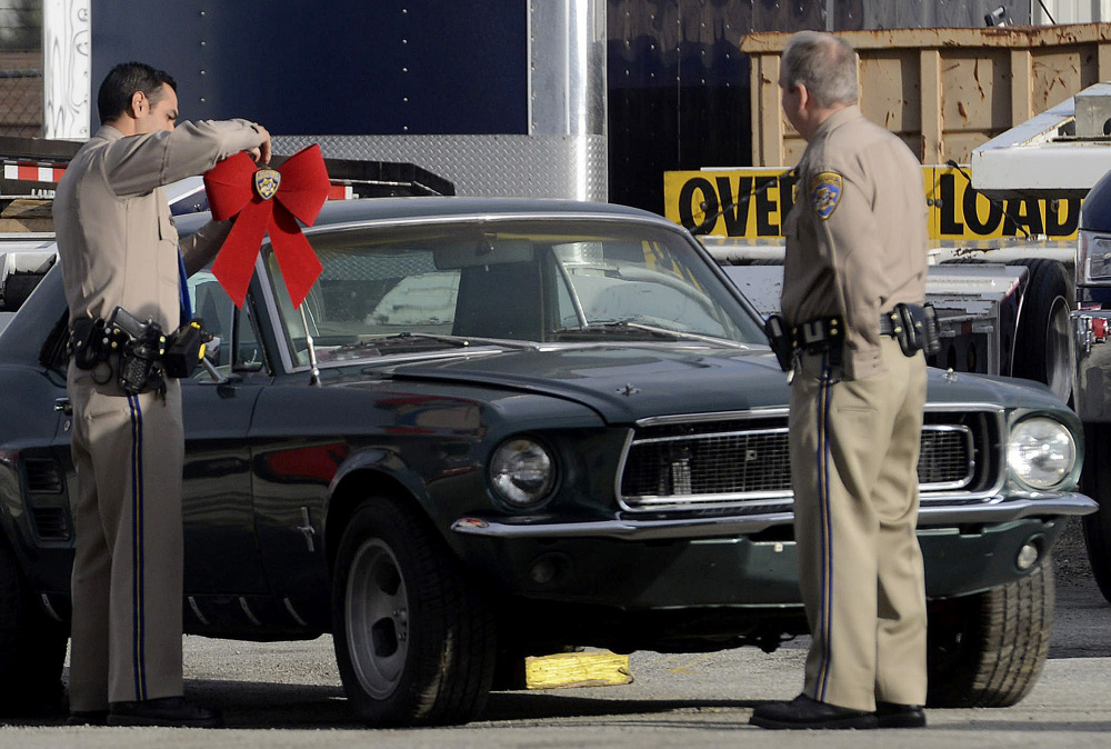 California Highway Patrol officer Jaime Rios, left, puts a bow on a 1967 Ford Mustang that was stolen in 1986 and is now being returned to the owner.