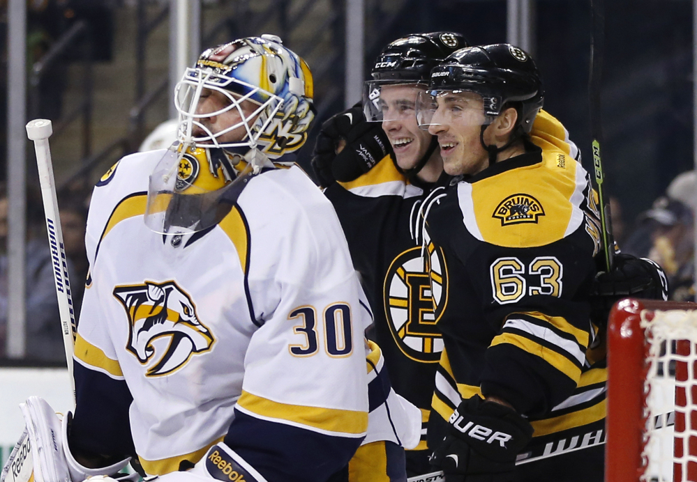 Boston Bruins left wing Brad Marchand (63) celebrates his goal with teammate Reilly Smith as Predators goalie Carter Hutton looks on during the second period of Tuesday night’s game in Boston. Marchand scored two goals in the game.