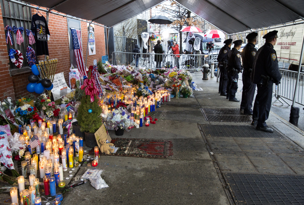 New York City police officers stand at a makeshift memorial Tuesday, near where two fellow police officers, Rafael Ramos and Wenjian Liu, were shot and killed in an apparent ambush in the Brooklyn borough of New York.