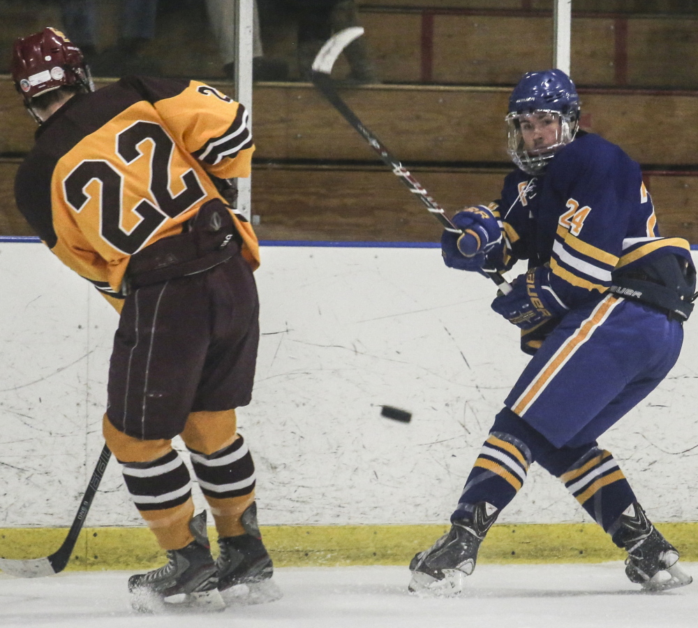 PORTLAND, ME - DECEMBER 23: Falmouth player Jake Grade hits the puck toward Cape Elizabeth's goal while Cape Elizabeth player Jack Drinan defends at the Portland Ice Arena in Portland, ME on Tuesday, December 23, 2014. (Photo by Whitney Hayward/Staff Photographer)
