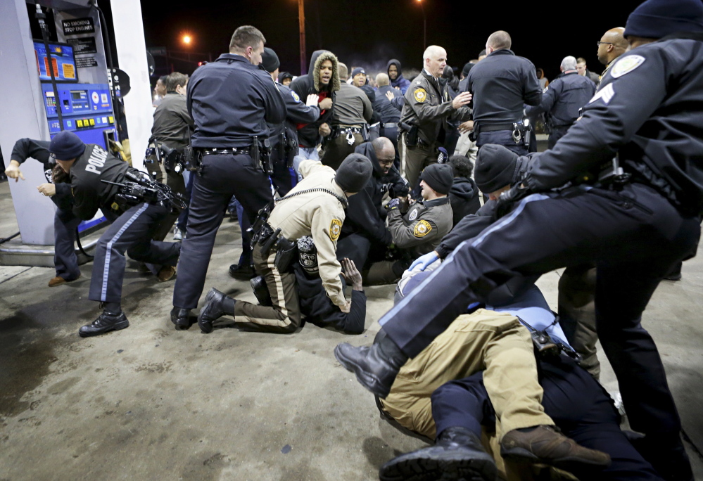 Police try to control a crowd on the lot of a gas station following a shooting Tuesday in Berkeley, Mo.