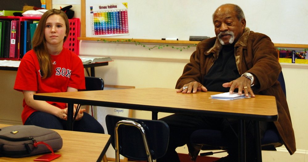Karissa Kenyon, an eighth-grader at Wells Junior High School sits at the front of the class with former Red Sox pitcher Luis Tiant, a native Cuban who spoke with students as part of a class project on immigration. Karissa did a project detailing immigration’s effect on Major League Baseball.
