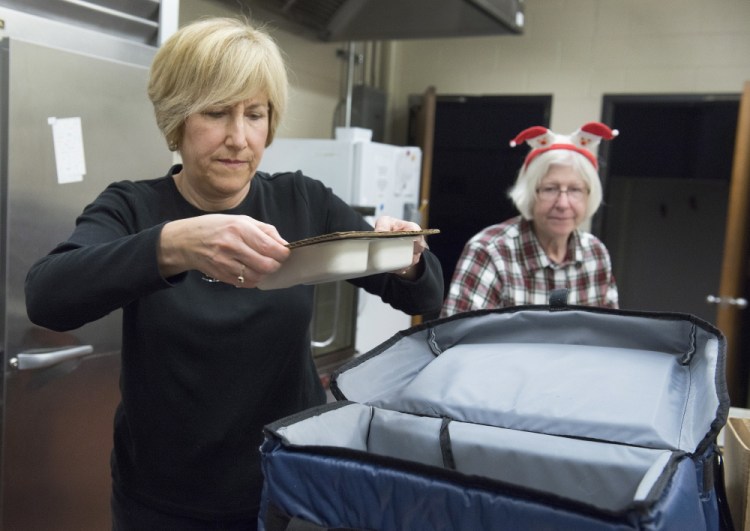 Volunteer Jackie Harkins of Portland puts a hot meal into an insulated carrying bag for delivery to a homebound senior on Christmas Day. Staff from the Southern Maine Agency on Aging and volunteers from the Portland Rotary Club joined in the holiday spirit of giving. At right is Deb Welton.