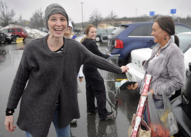Karyn Sweeney, left, hands Sierra Warner of Monmouth a gift Wednesday in the parking lot of Wal-Mart in Augusta. “This is probably the best Christmas I’ve ever had in my life,” Sweeney said. “There are lots of free hugs.”