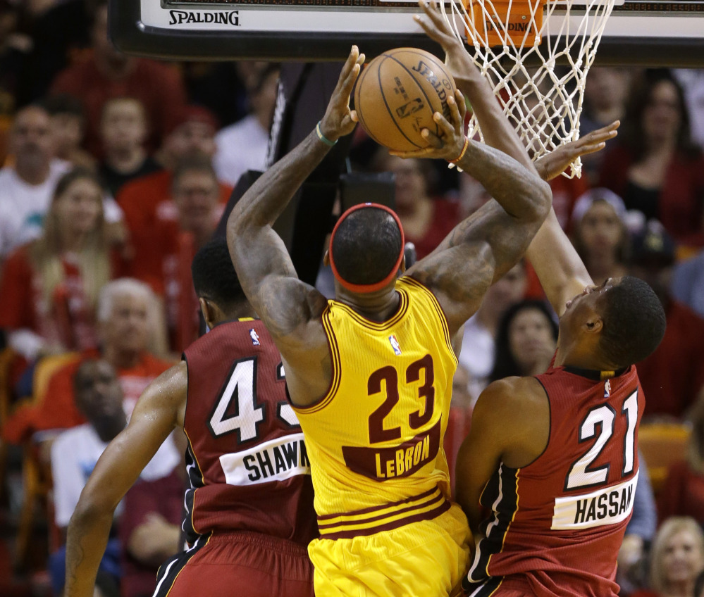 LeBron James of the Cleveland Cavaliers heads to the rim between Shawne Williams, left, and Hassan Whiteside of the Miami Heat during the first half of Miami’s 101-91 victory.