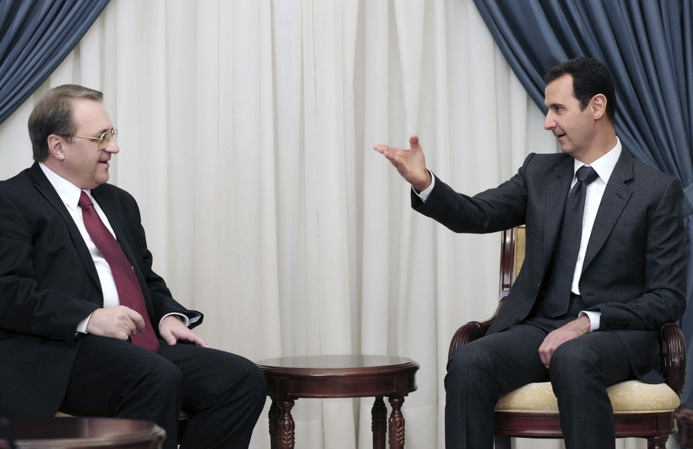 Syrian President Bashar Assad, right, speaks with Russia’s Deputy Foreign Minister Mikhail Bogdanov on Dec. 10 in Damascus. The search for a negotiated settlement to the Syrian civil war is gaining steam.