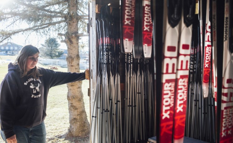 Hillary Knight, barnyard and cross-country ski manager at Smiling Hill Farm in Westbrook, looks at the rental skis Friday. “It would be nice to have some snow on the ground, some people here and some income coming in,” she said.